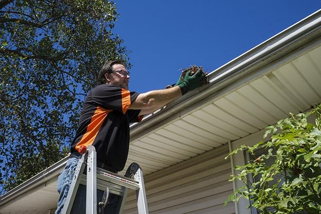 a homeowner repairing their gutter with tools in Caldwell